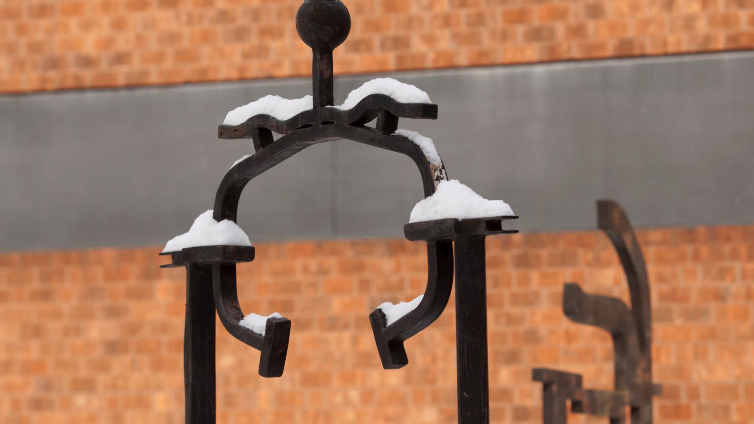 Players sculpture by Steven Feren in front of Art History Hall in the snow on Douglass Campus