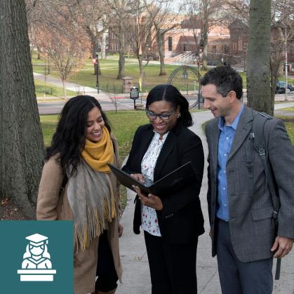 Three smiling faculty members look at information in a folder